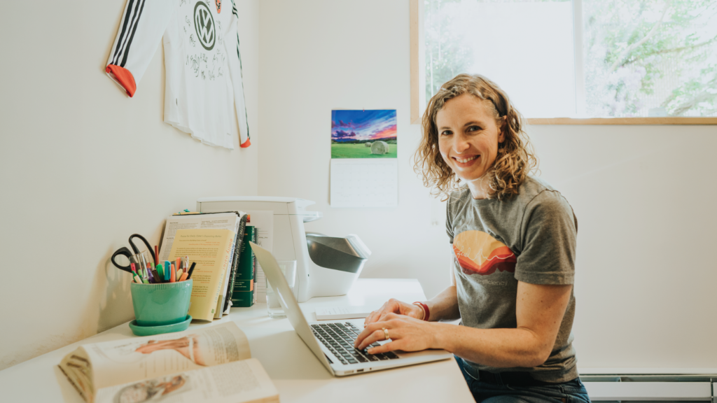 Nicole Bulow smiles at a laptop in her home office, where she runs SolFuel physical therapy